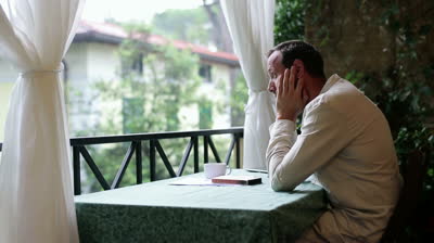 stock-footage-sad-man-sitting-alone-on-his-balcony